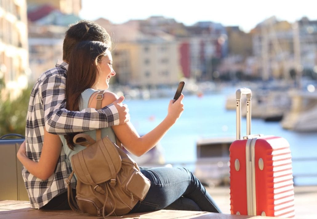 Tourist couple booking a hotel on their smartphone while traveling in Europe.