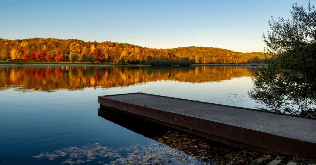 Bucolic view of a river in the US framed by trees during the peak of the fall foliage. 