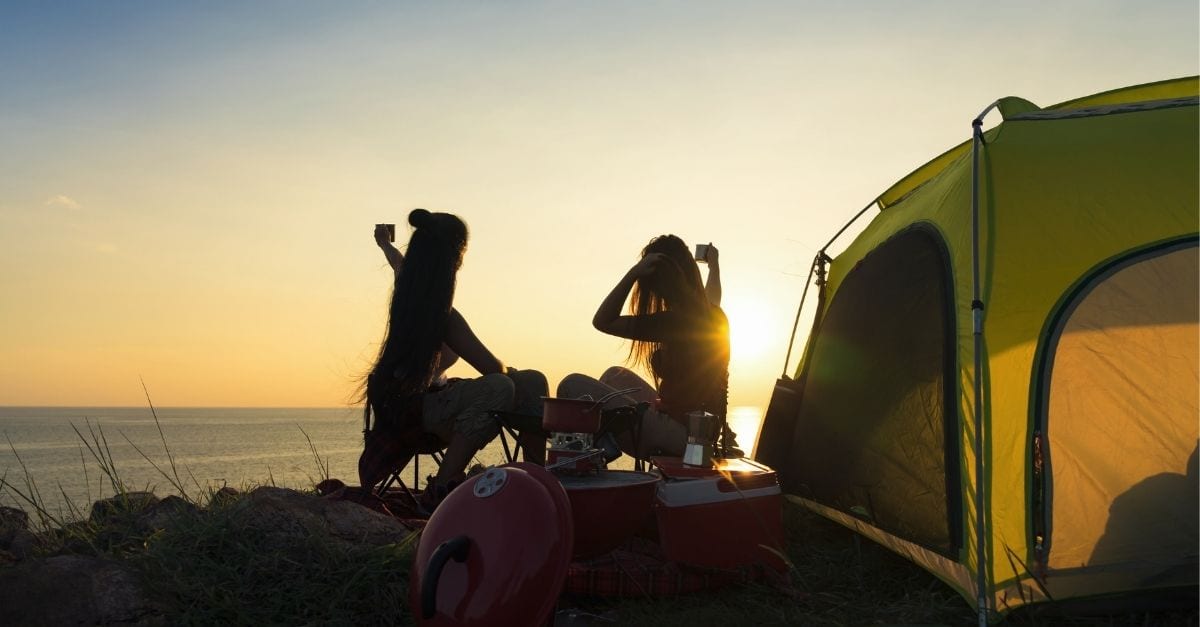 Two best friends taking a selfie during sunset while camping.