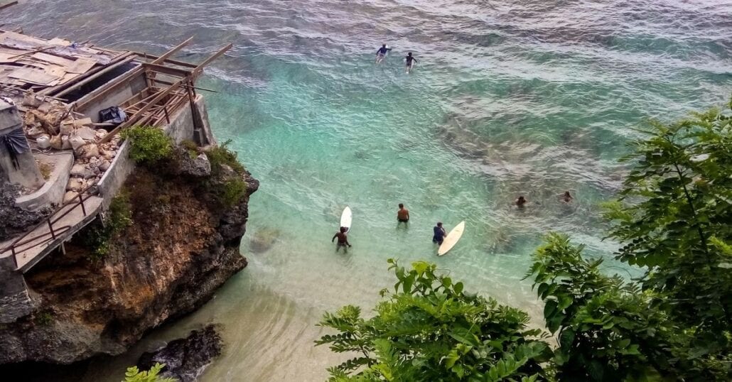 Aerial view of the transparent blue water filled with surfers at the Blue Point Beach, in Pali.