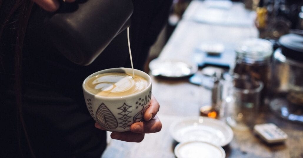 A barista making a latte art on a cup of coffee.