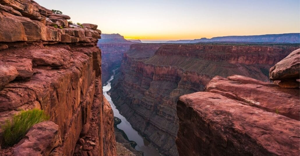 View of some of Grand Canyon’s red-coloured rocks during an orange sunset.
