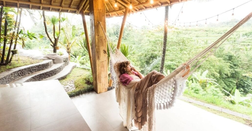 A woman lying in a hammock at a hotel surrounded by nature, in Bali.