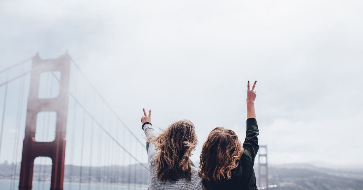 Mom and daughter doing the peace sign in front of the Golden Gate Bridge, in San Francisco.