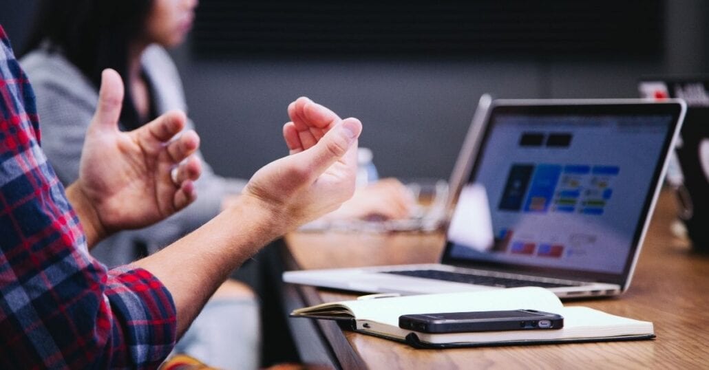 Person working with colleague in fron of a laptop.