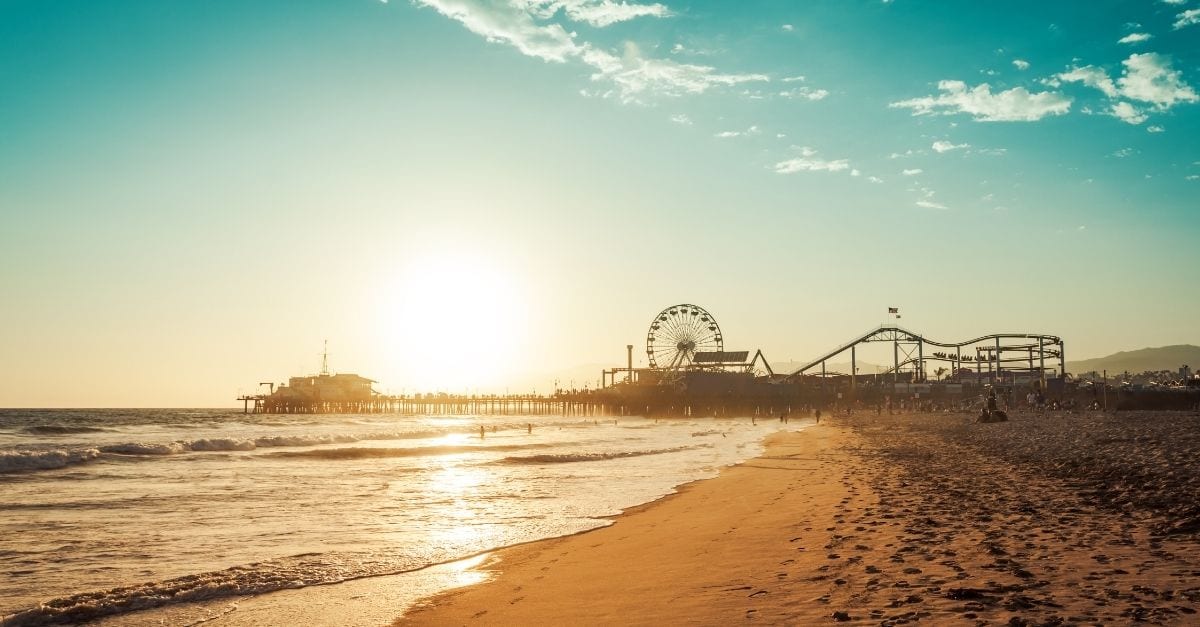 View of the Santa Monica Pier from a beach during the sunset.