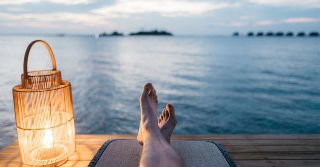 Men relaxing at a wooden deck at dawn by a river. 