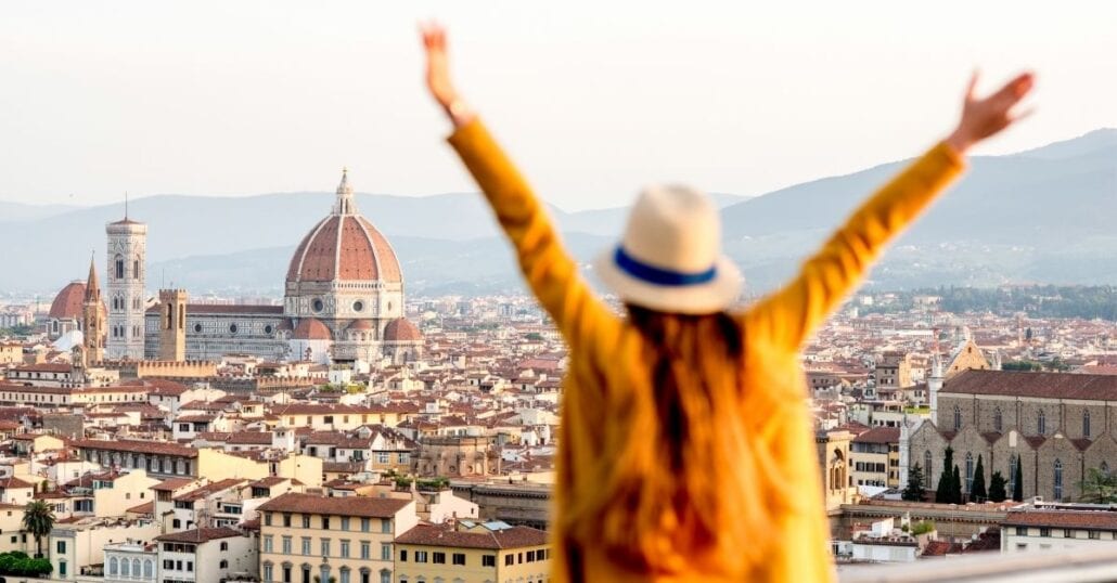 Happy girl with her arms wide open in front of the Florence Cathedral, in Italy.