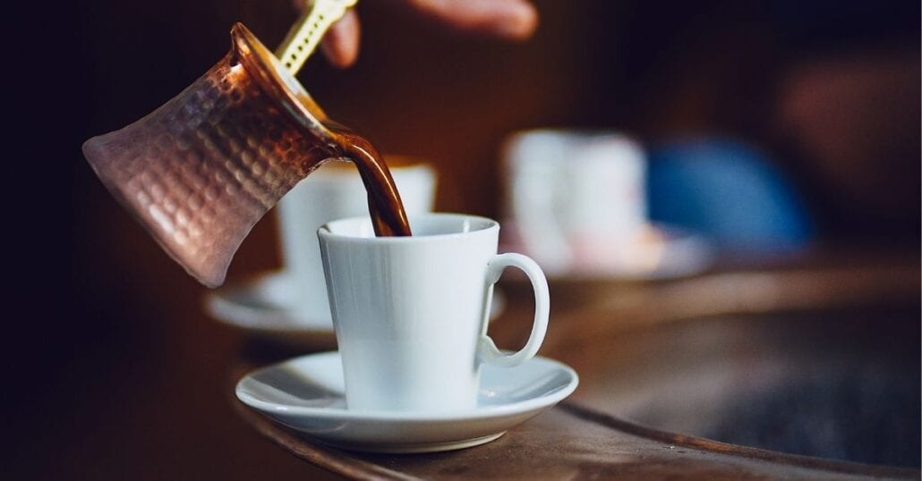 Turkish coffee being poured on a white cup.