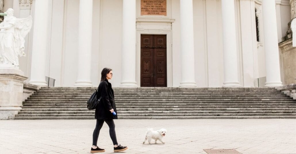 Woman walking with her unleashed white poodle in Vienna, Austria.