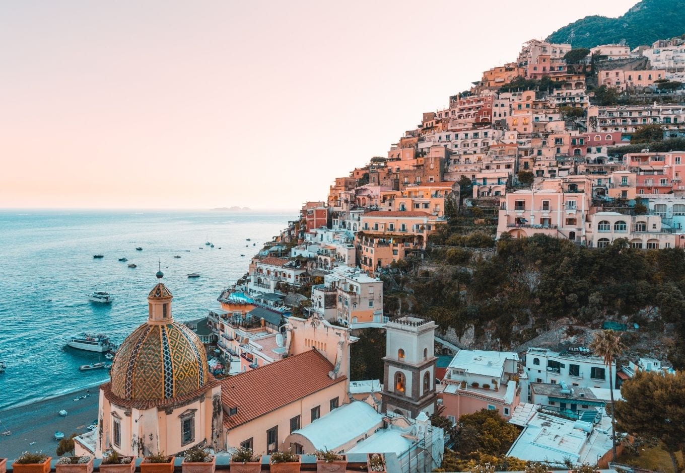 The Amalfi Coast dotted with pink-hued houses at dusk.