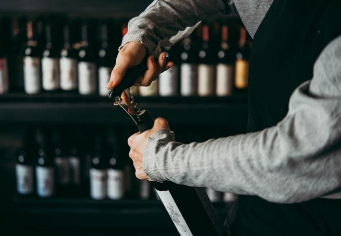 A sommelier opening a bottle of wine at a wine bar.