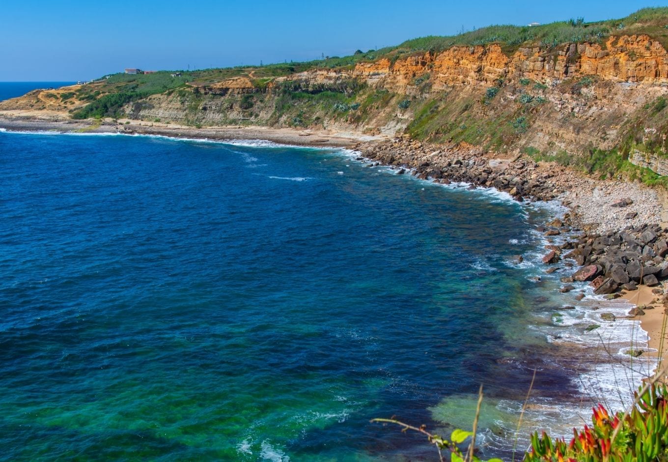 Aerial view of the ocean surrounded by a cliff in Ericeira beach, Portugal.