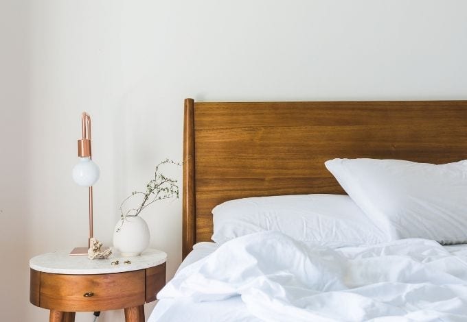 An unmade hotel bed with white sheets.