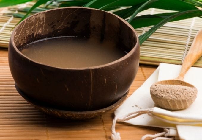 A Kava drink being served on a coconut shell.