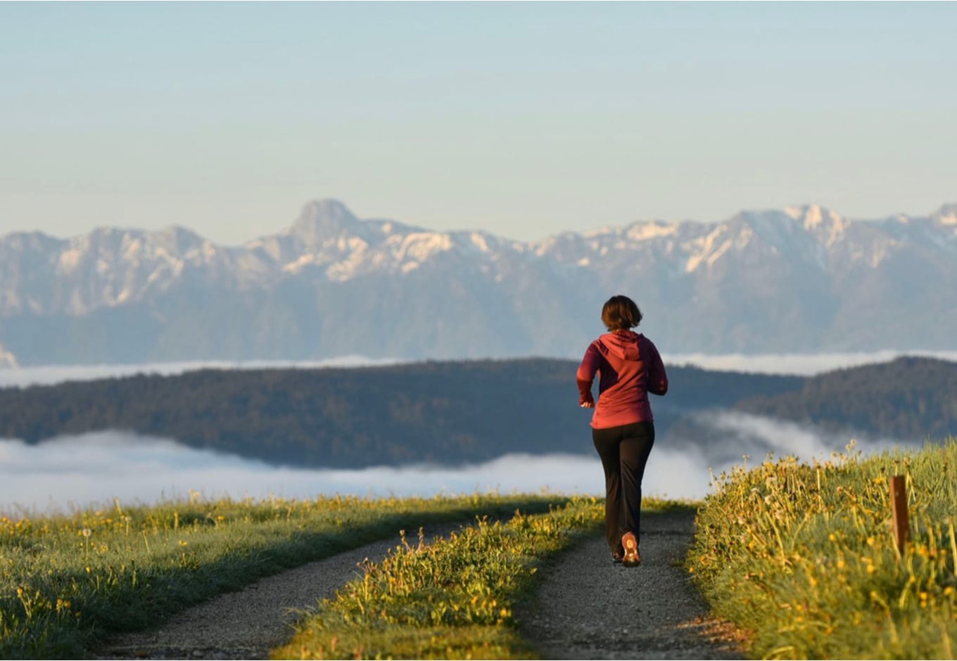 Woman running towars a snowy mountain range.