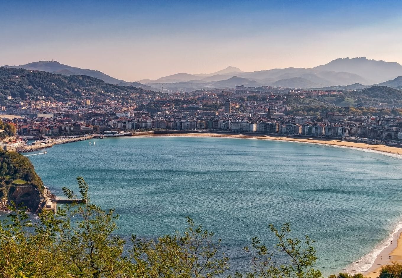 View of the ocean surrounded by buildings and mountains in San Sebastian, Spain.