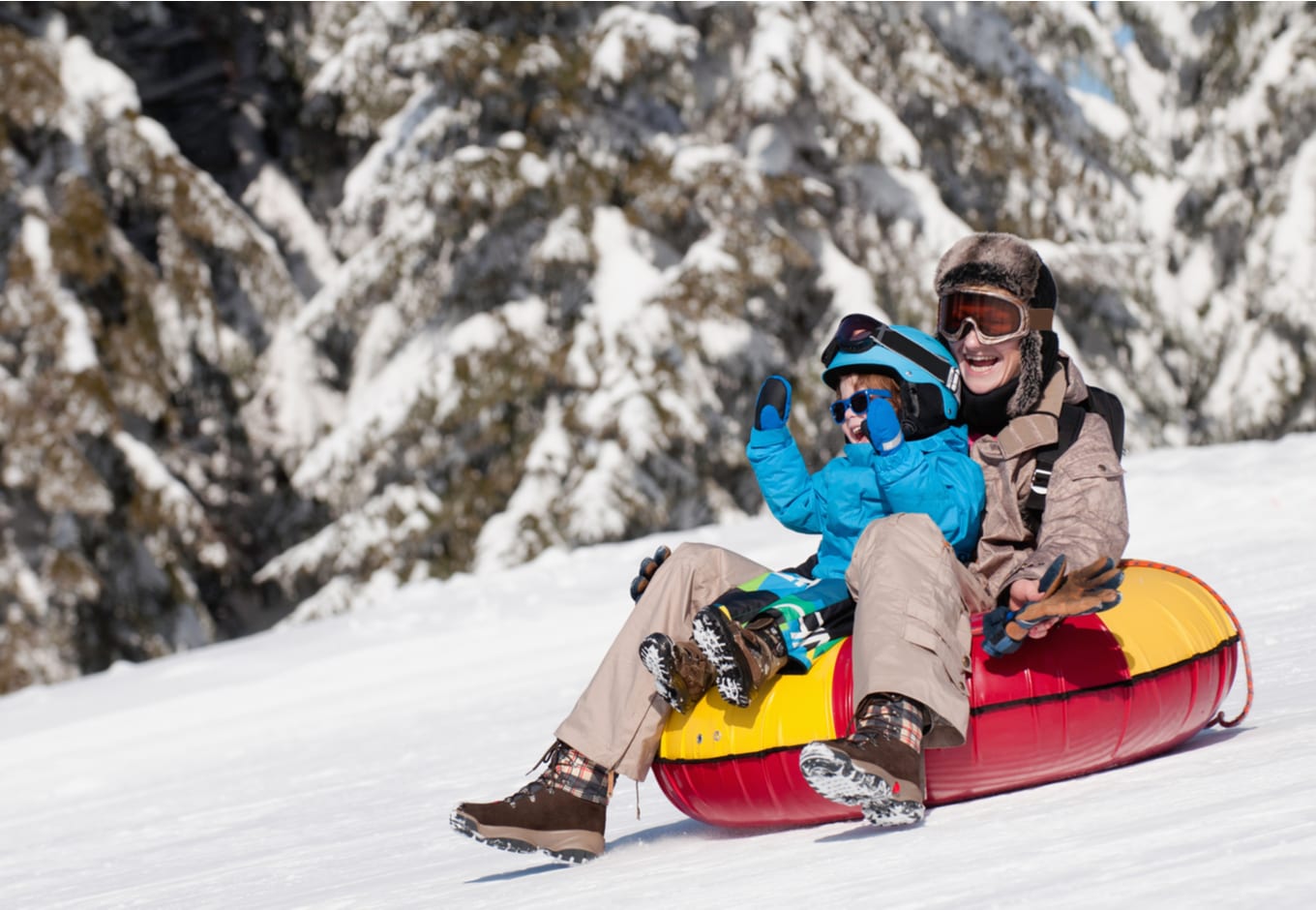 Woman and child sliding down in inflatable snow tube
