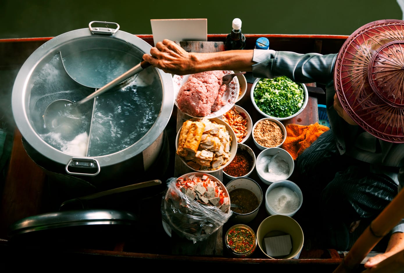 Vendor preparing street thai food on a boat over the floating market, in Thailand.