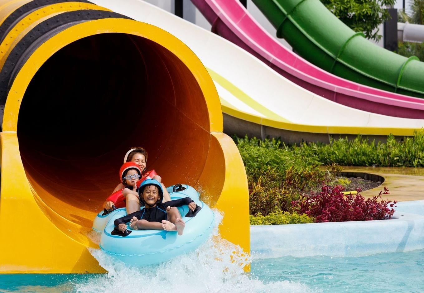 A mother and two kids sliding down a a giangt tube at a water park.