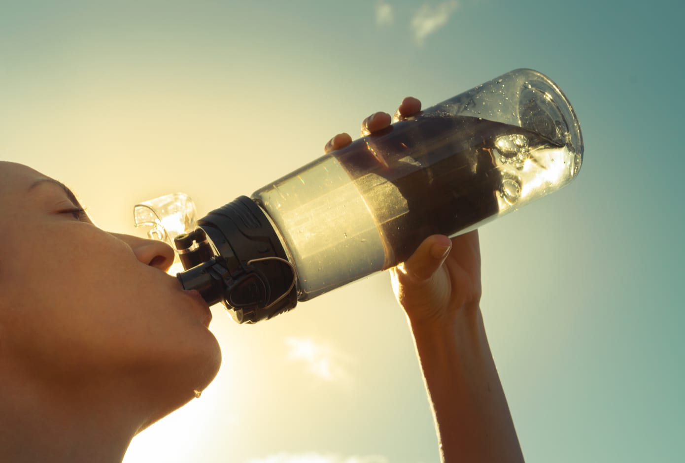 Young woman drinjing water from an acrylic bottle.