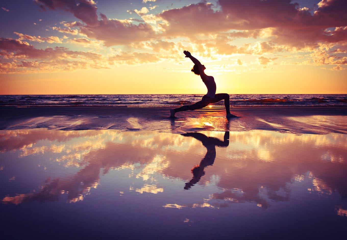 Woman practicing yoga at the beach.