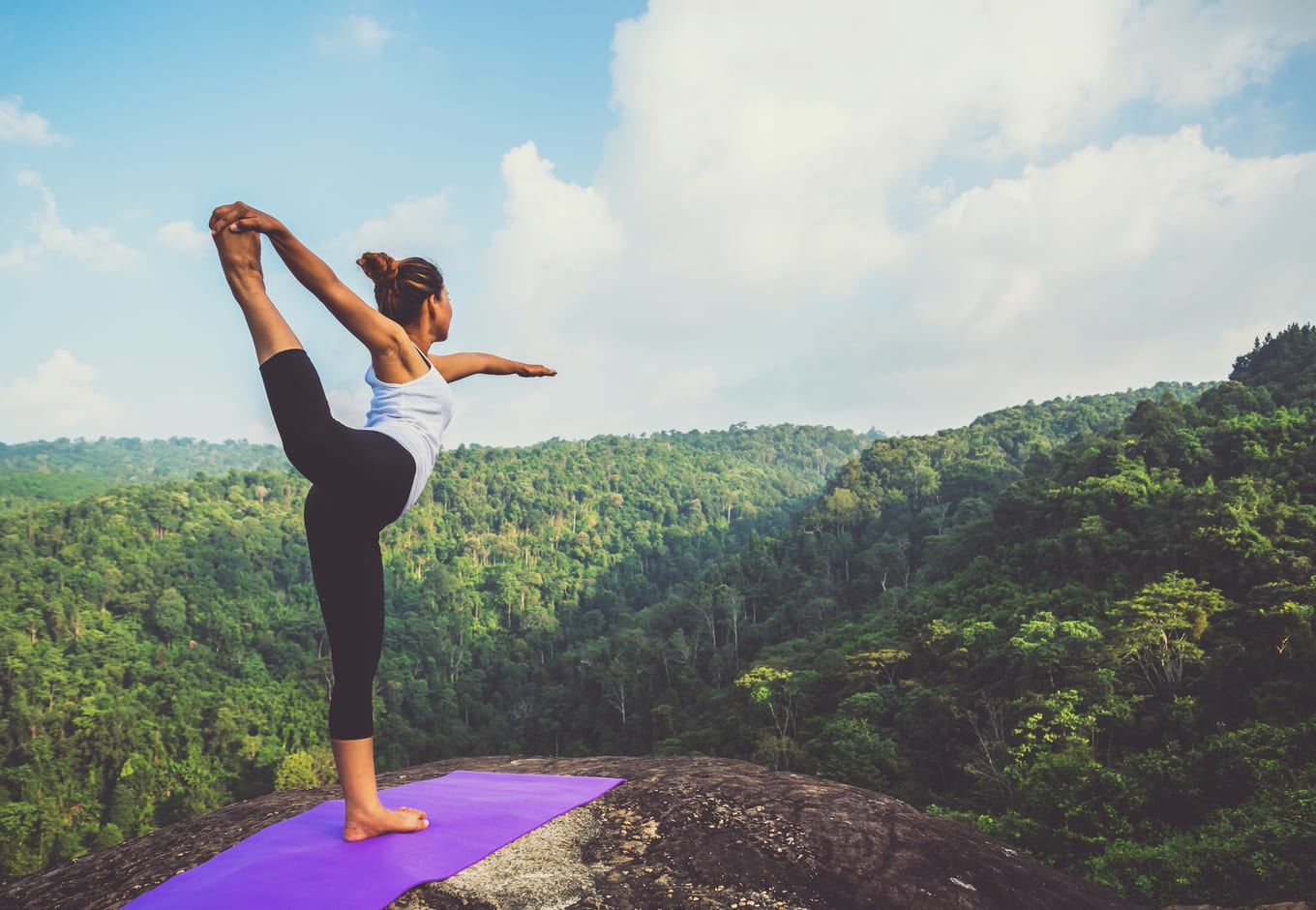 Woman practicing yoga at the top of a mountain in Thailand.
