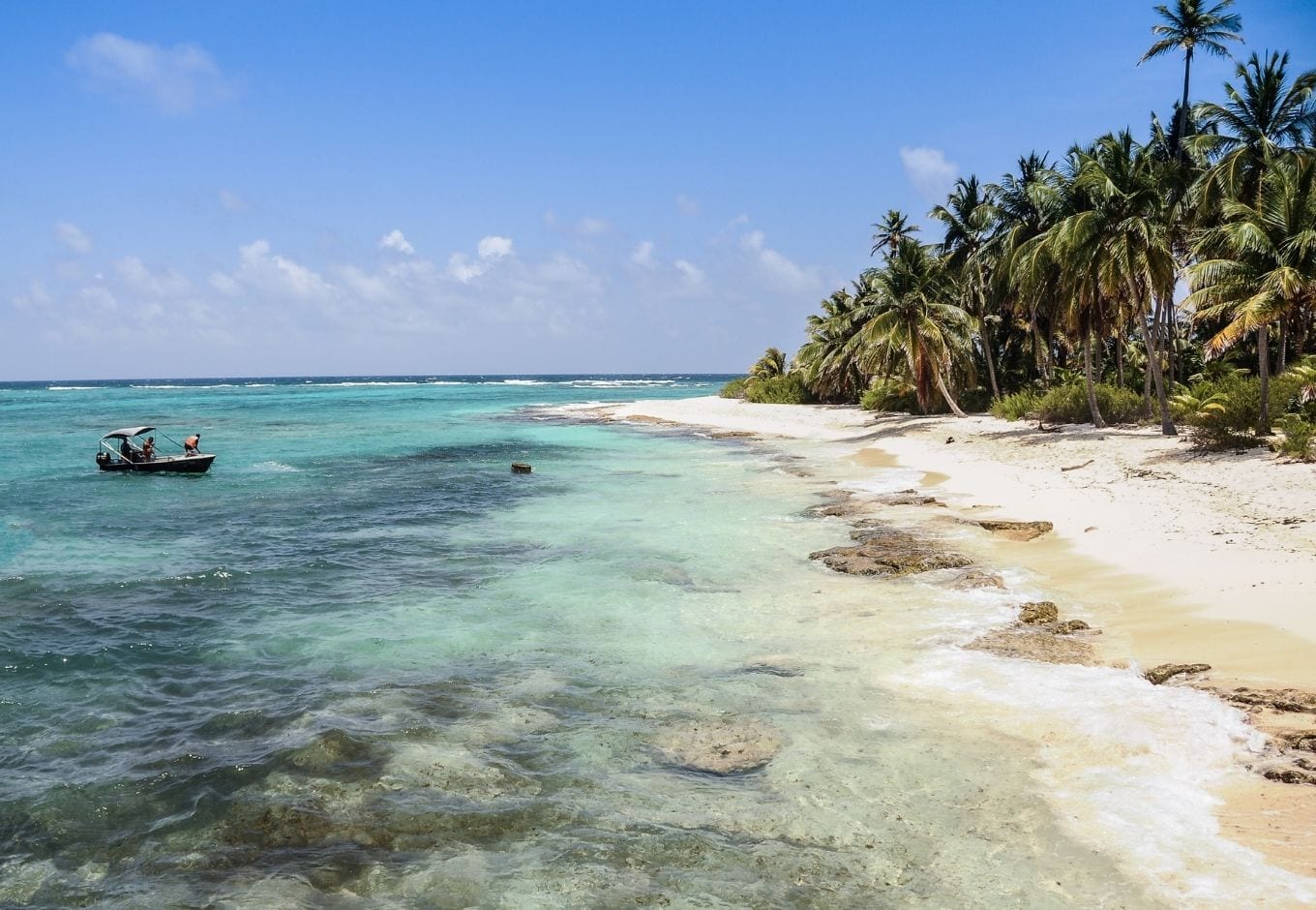 White sandy beach with palm trees and transparent blue-green water at San Andrés, in Colombia, South America.