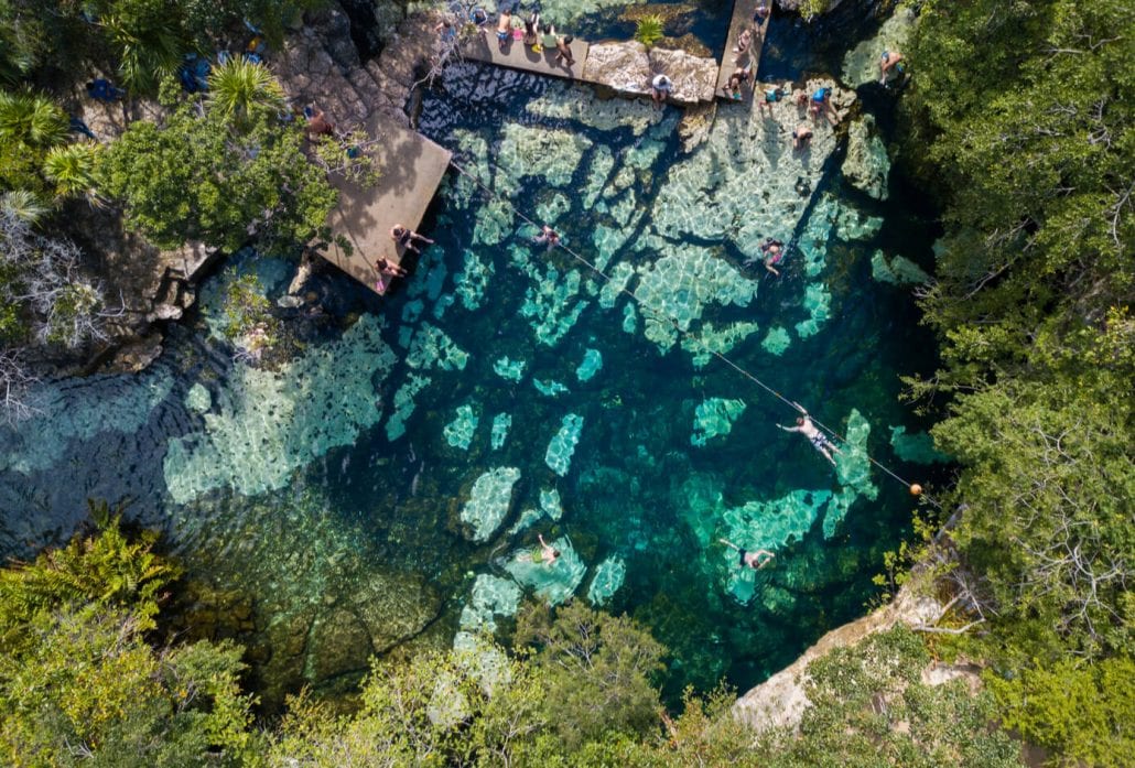 Tree people swimming in the turquoise-waters of the Samula Dzitnup Cenote, Mexico.