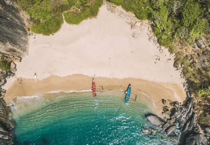 Secret beach in Goa, India. Aerial view to pristine beach with rocky bay and crashing waves