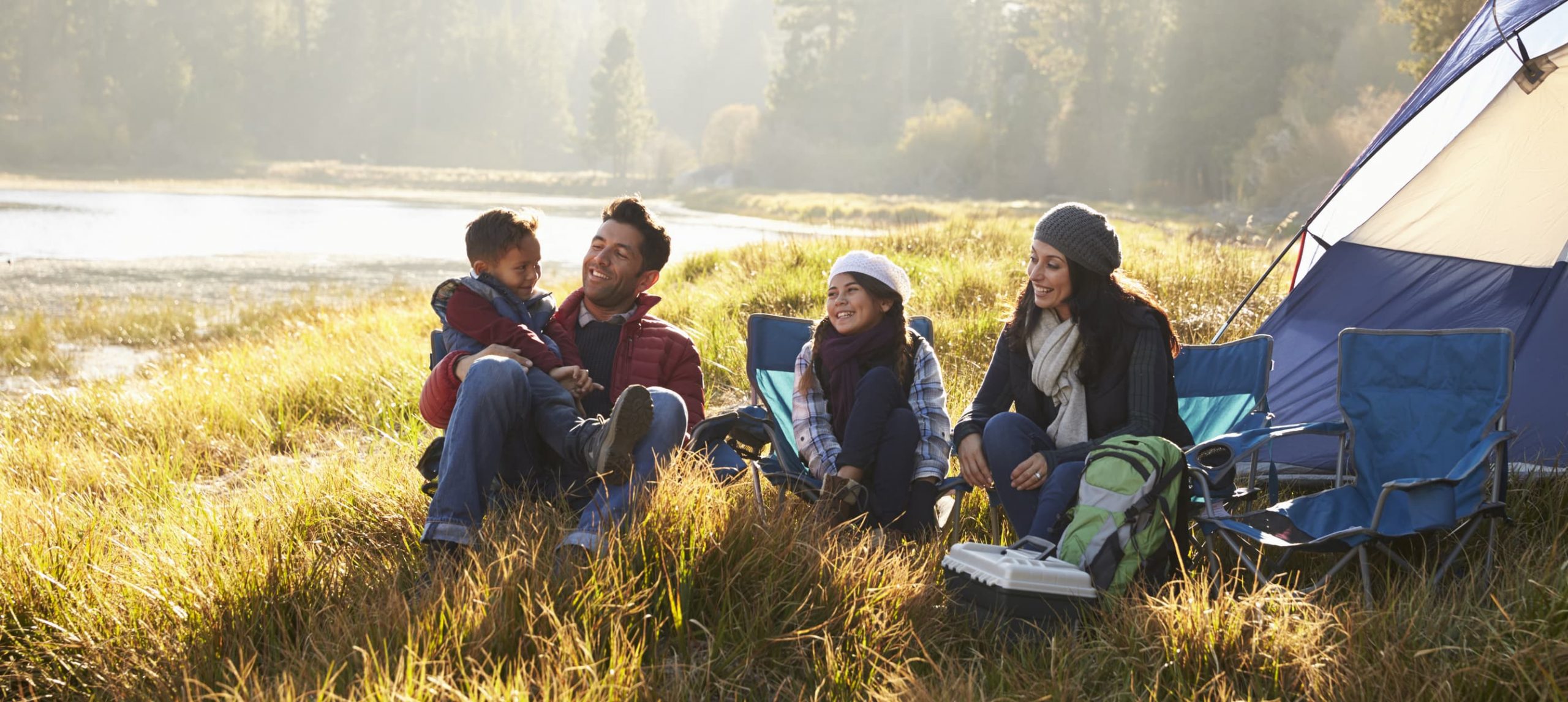 A couple with two kids camping in the nature.