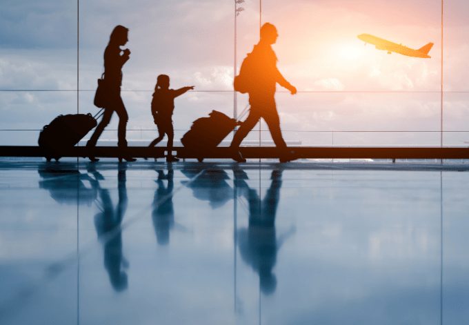 Silhouette of young family walking at the airport and and an airplane on the background.