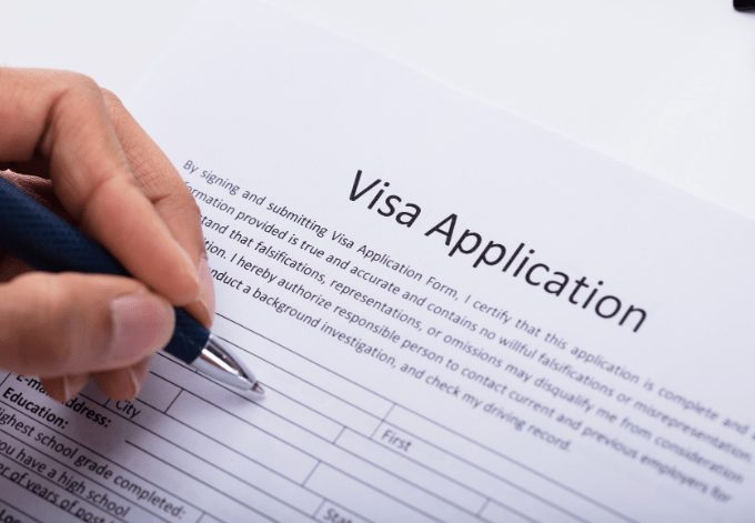 Close-up of a Person's Hand Filling Visa Application Form