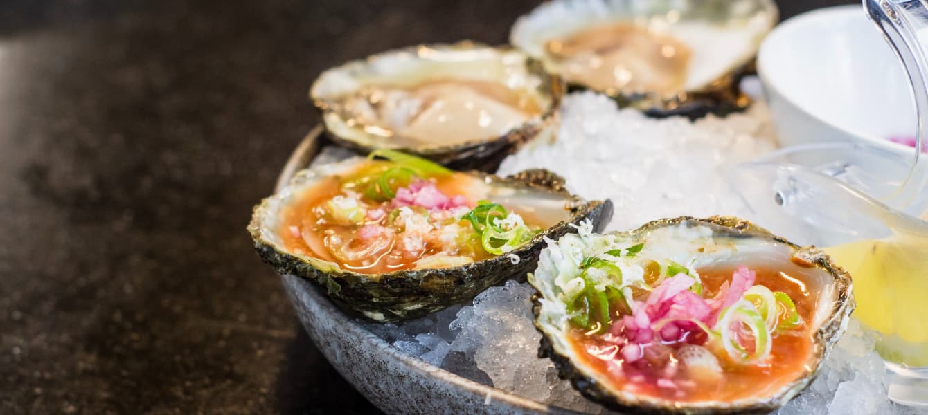 A plate with four beautifully seasoned oysters.