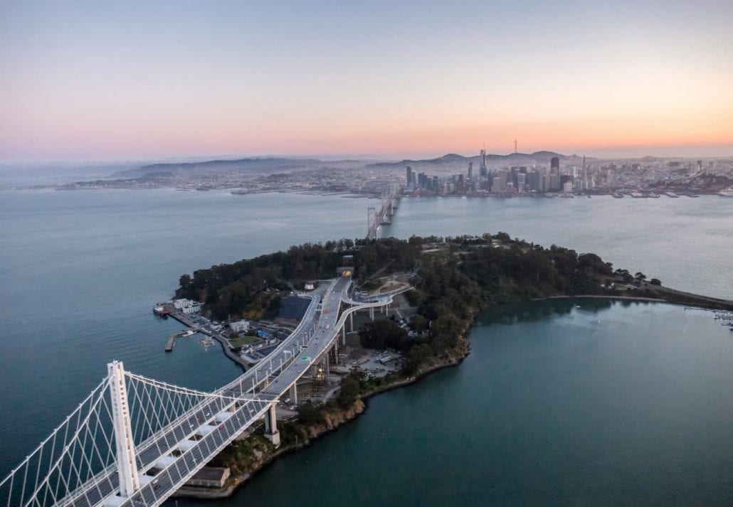 An aerial view of the Bay Bridge and Treasure Island with the City of San Francisco in the background.