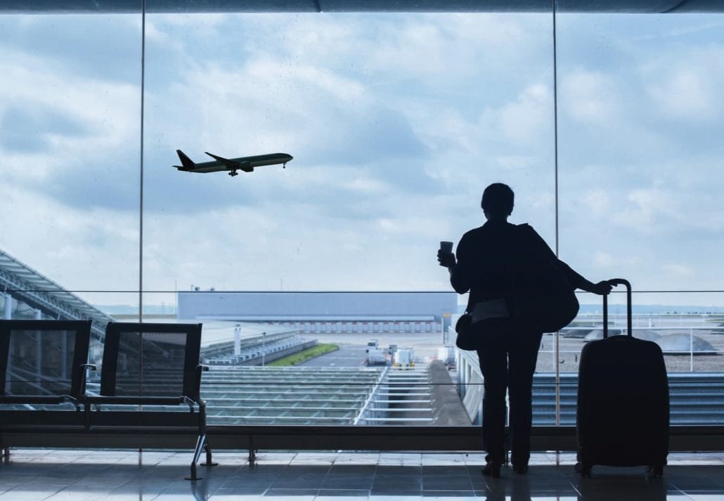 Traveler at the airport watching a plane take off.