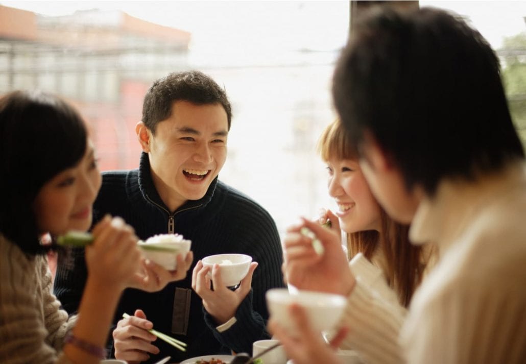 Group of Chinese friends eating rice and laughing.