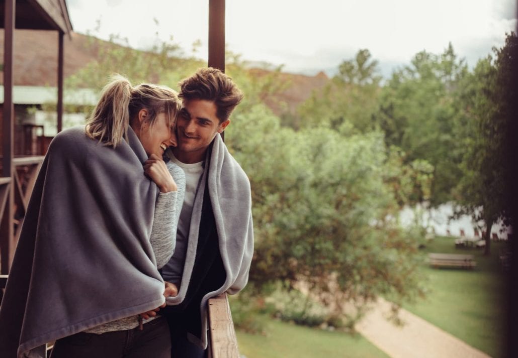 Romantic couple in a blanket standing together on a winter holiday.