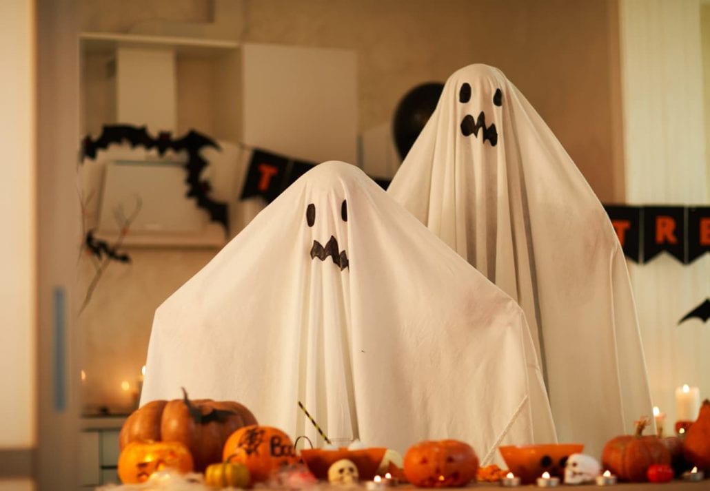 Portrait of children dressed in ghost costumes they standing in the room and celebrating Halloween