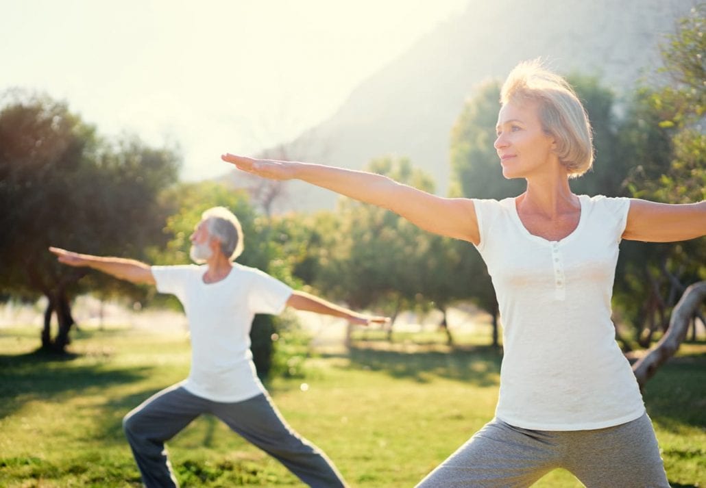 Senior couple doing yoga outdoor.