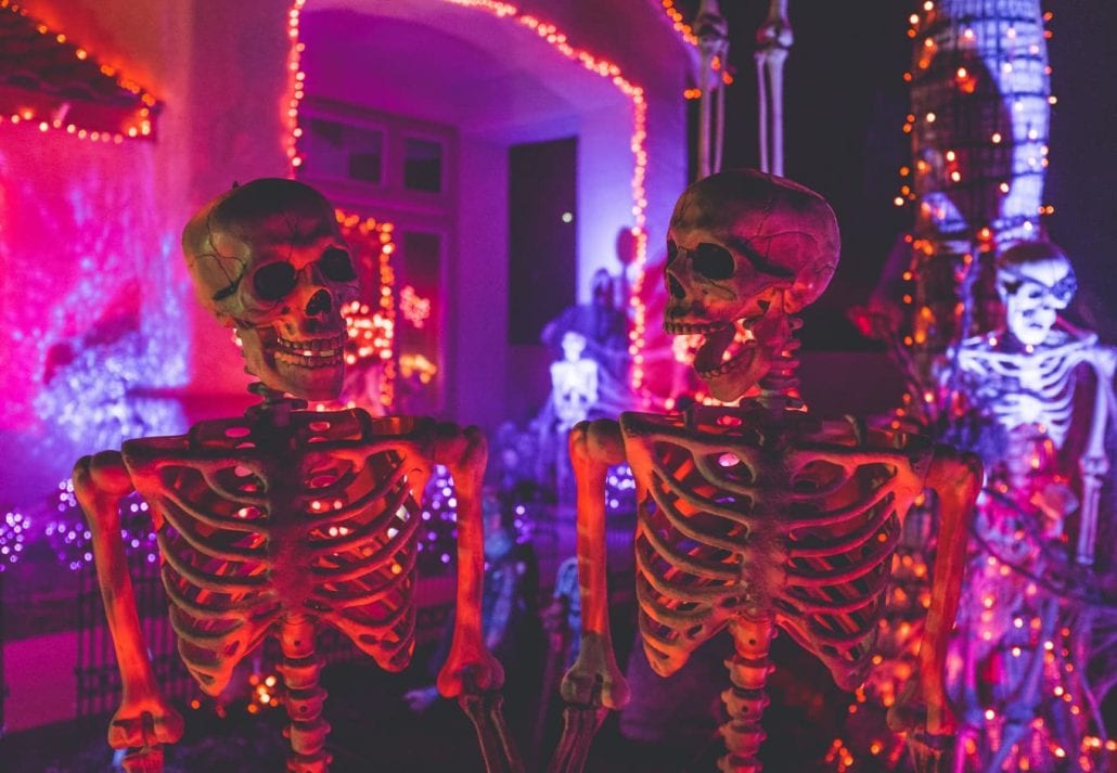 Halloween decoration with skeletons and lights at a house at night.