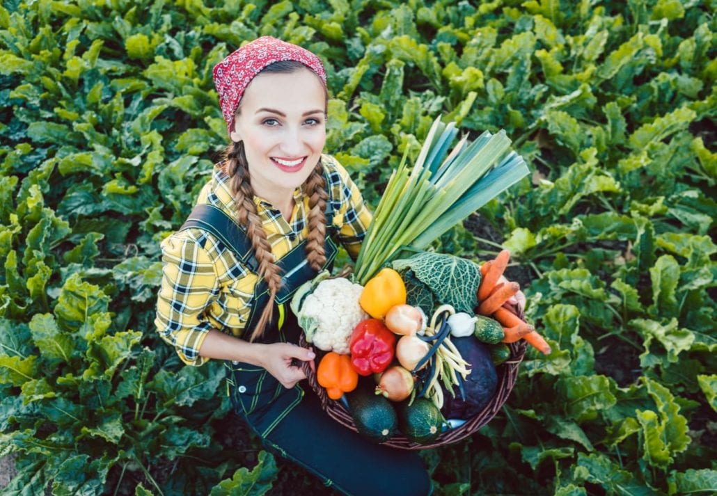 Farmer woman in a field offering colorful organic vegetables as healthy food