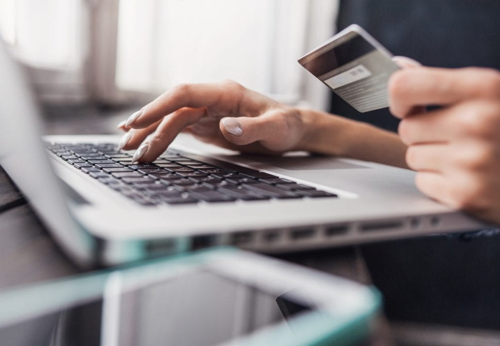 Woman holding a credit card and shopping online on her laptop.