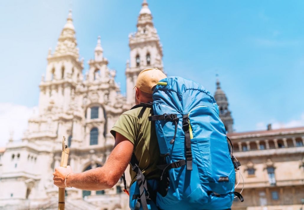 Backpacker man pilgrim looking at Santiago de Compostela Cathedral standing on the Obradeiro square (plaza)