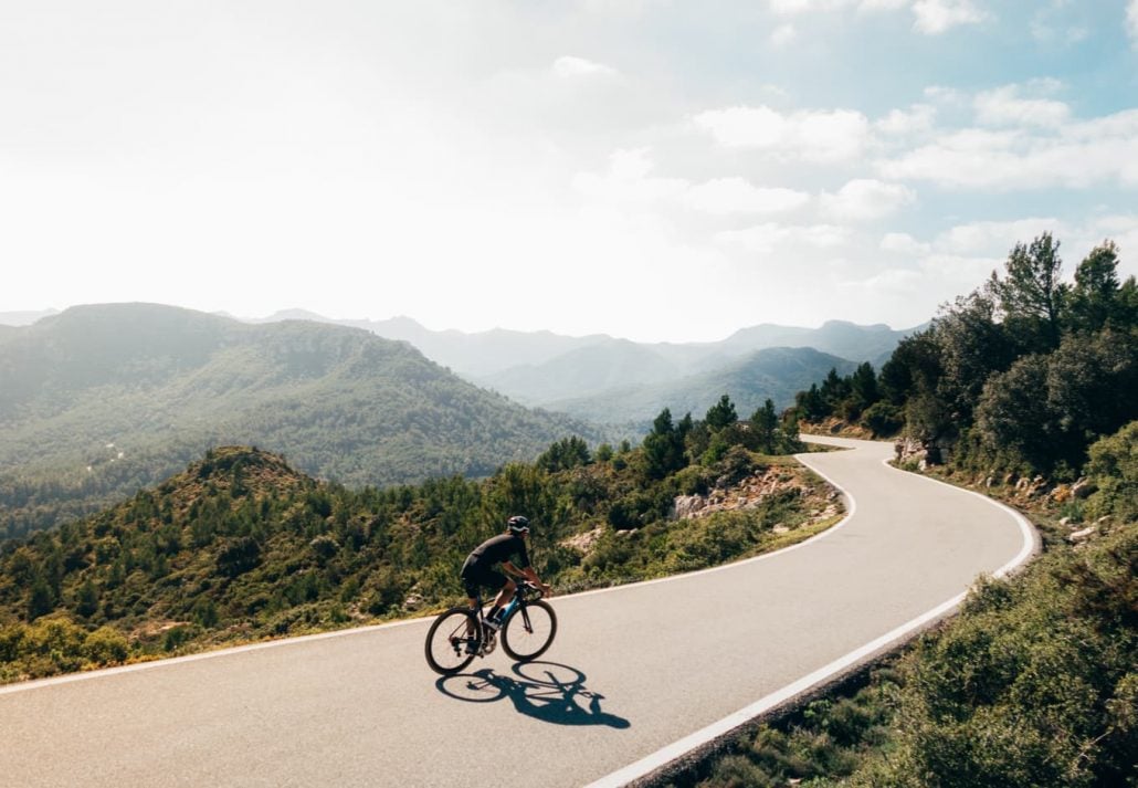 Cycling through a road surrounded by mountains.