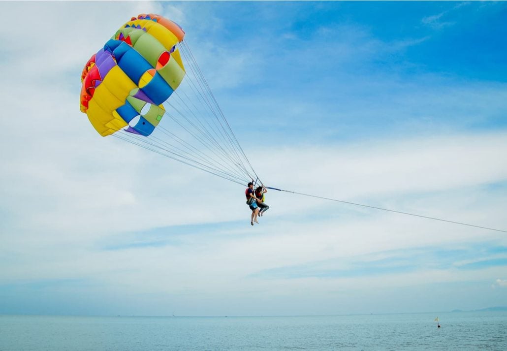 Tourists parasailing in the blue sky over the ocean.