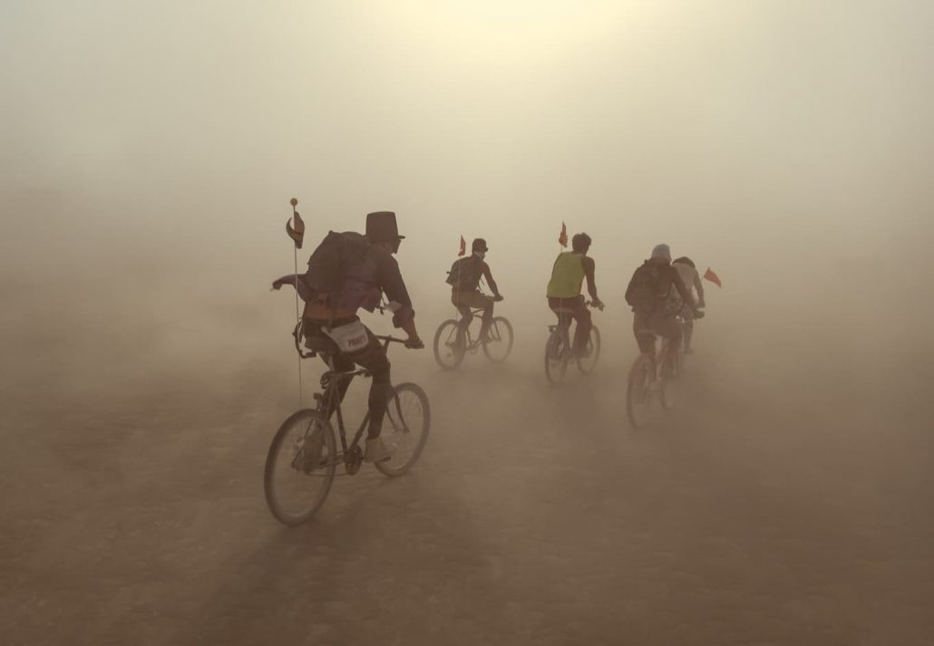 Group of people riding on bikes in dust storm