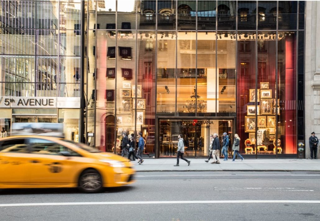 Midtown Manhattan street view along the upscale shopping district on 5th Avenue with cars and people.