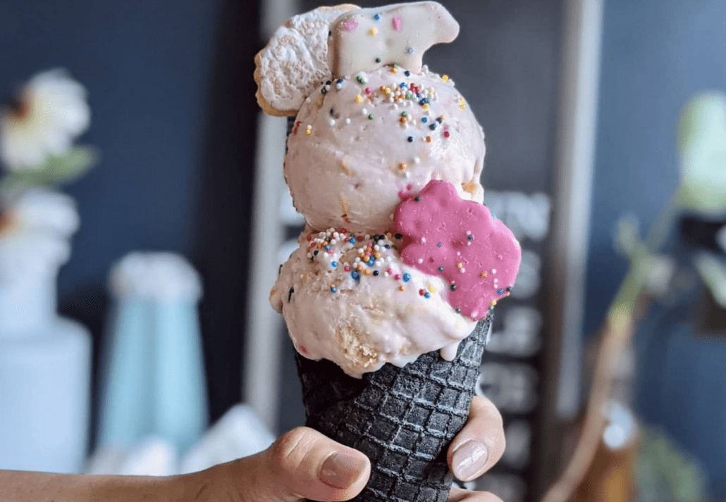 A young girl holding a cone with three scoops of ice cream.