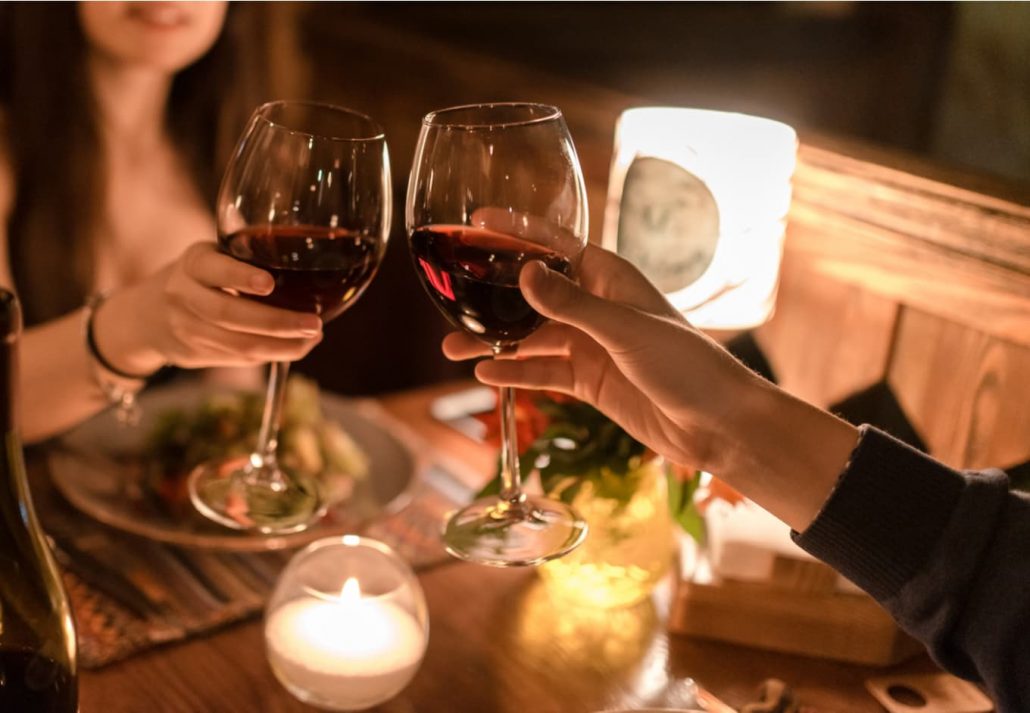 valentines-day-orlando-romantic-dinner | CuddlyNest Travel Blog Young couple toasting with red wine during a romantic diner.
